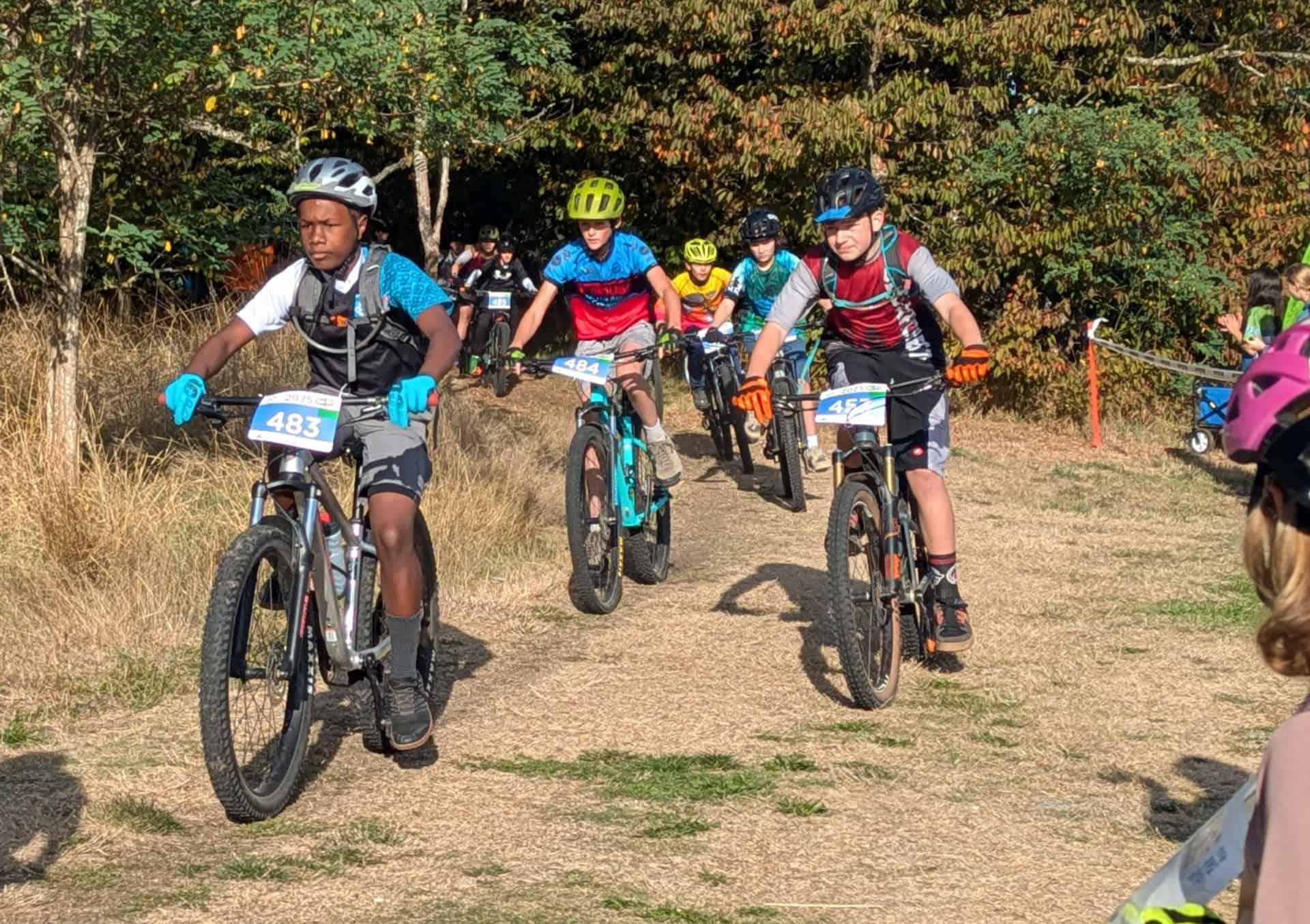 Multiple cyclists racing on mountain bike course. 