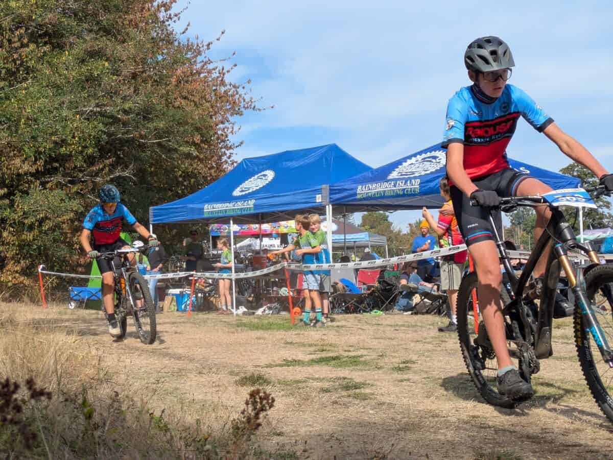 Two cyclists on course with team tent in background