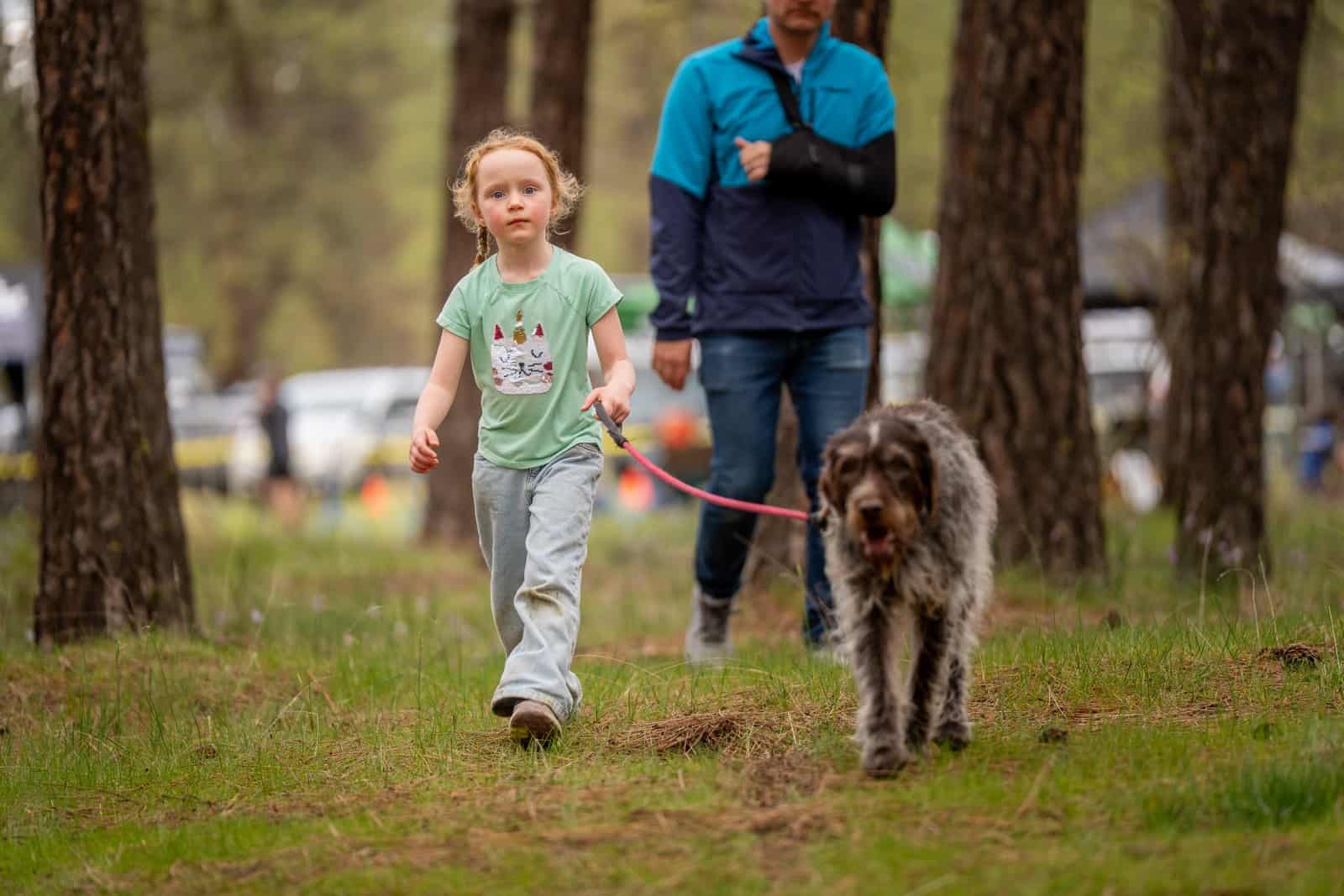 A young spectator walking a dog along the course at Riverside Rampage